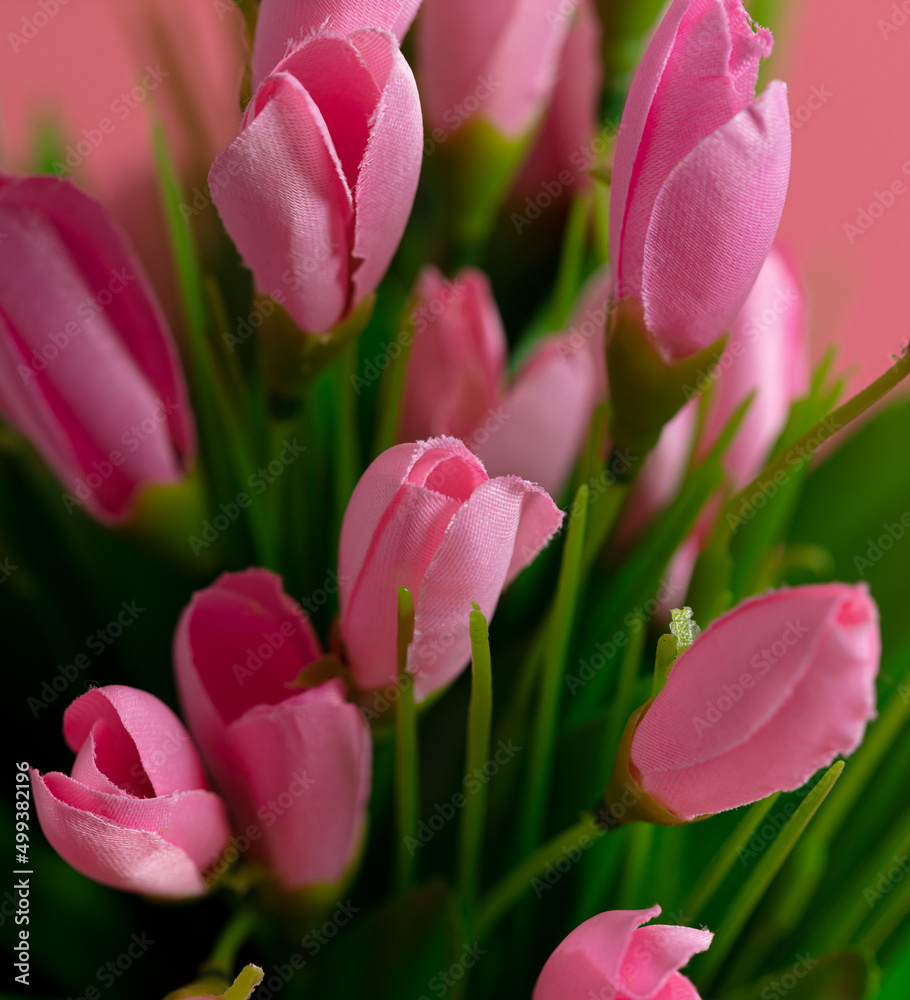 Fototapeta premium Artificial pink flowers on a pink background.