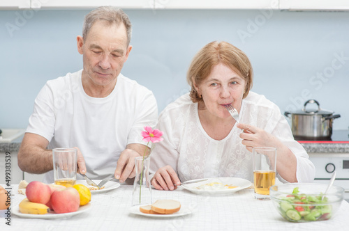 Elderly couple having breakfast together in the kitchen at home