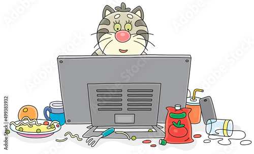 Funny plump cat gamer playing a very interesting computer game and intently looking at a monitor among a mess on its desktop, vector cartoon illustration on a white background