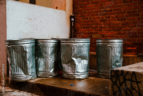 empty battered traditional american trash bins standing in a back alley in New York City