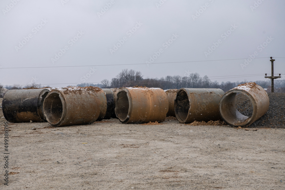 Pile of stacked concrete drainage pipes for wells and water discharges, ready for construction. Industrial background. Pile of stacked concrete drainage pipes for wells and water discharges, ready for construction. Industrial background.
