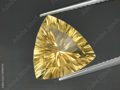 Принти на полотні Natural gemstone yellow citrine in tongs on a gray background