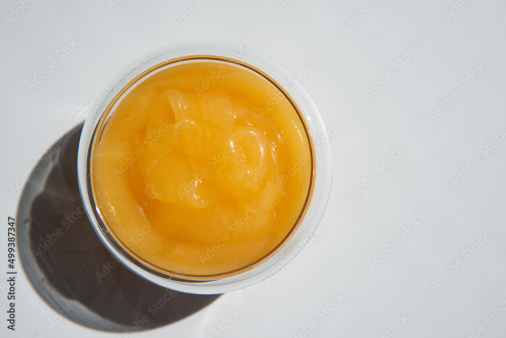 texture of golden honey in a transparent container on a white background free space for text.sunflower honey texture of golden honey in a transparent container on a white background free space for text.sunflower honey