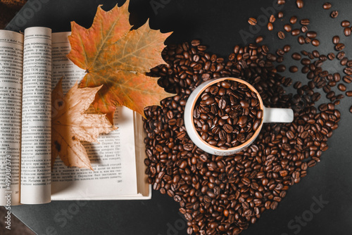 Heart-shaped coffee beans, dry autumn leaves and old book