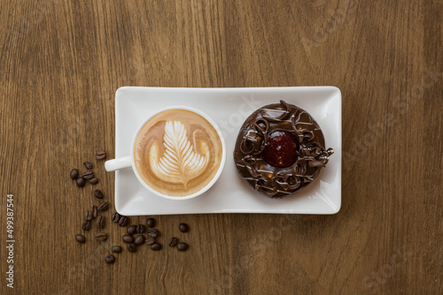 Top view of chololate donut and latte coffee on wooden table decorated with coffee beans photo