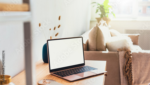 Laptop with blank white screen on office desk interior. Stylish rose gold workplace mockup table view. Panoramic banner © uv_group