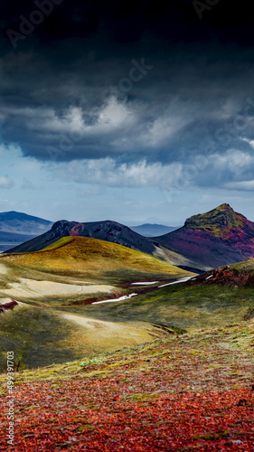 Cover page with colorful Icelandic rainbow volcanic Landmannalaugar mountains at famous Laugavegur hiking trail in Iceland, dramatic summer scenery, with rainy sky and copy space for text.