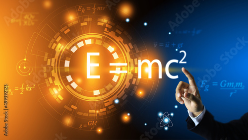 The teacher's hand points to the equation of relativity of Albert Einstein. E equals m multiplied by c squared. In the concept of a physics equation ring and a dark blue background. physics education. photo