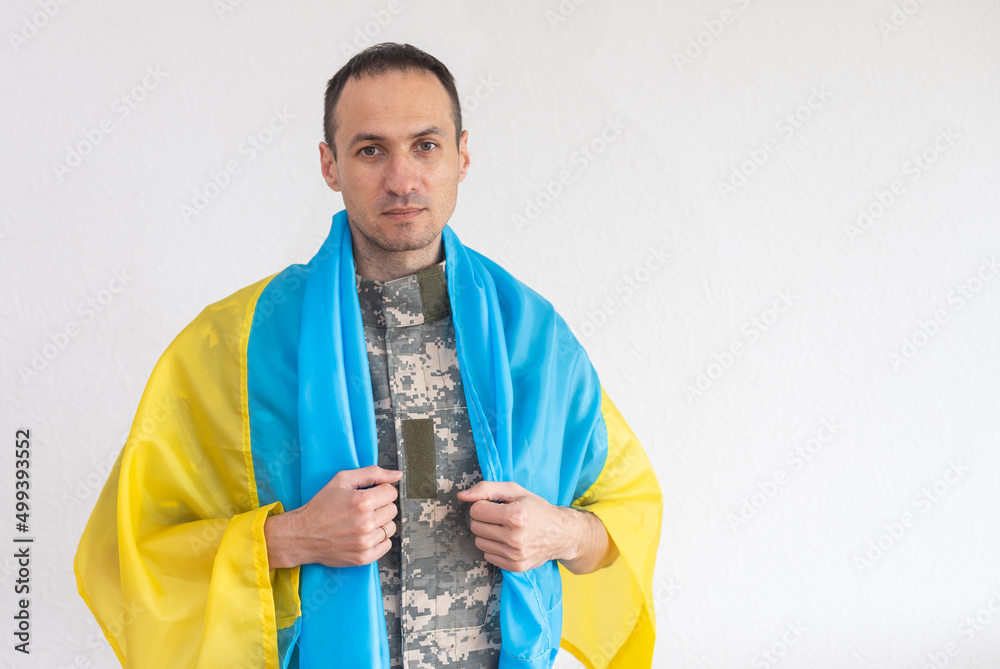Fototapeta premium Photo of ukrainian soldier in full body armor holding rifle with scope on devastated and ruined war city background. Stand with Ukraine