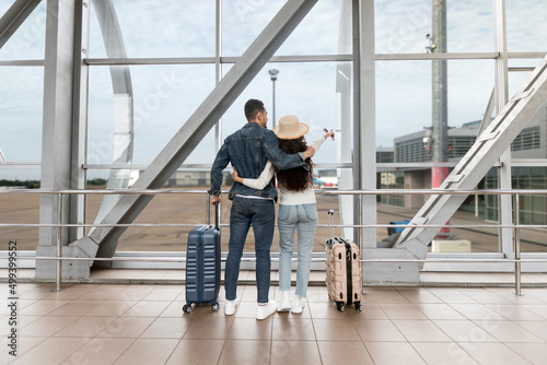 Couple With Suitcases Looking Of Window At Airport While Waiting For Flight