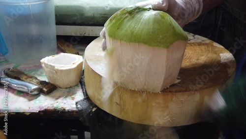 Man is peeling coconut with a knife.Green fresh coconut peeling and shelling with heavy chop knife for juice. 