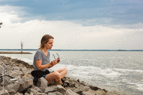 Beautiful girl on the sea overlooking the lighthouse and blue sky with clouds