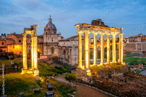 View of the temple of Saturn in Roman forum at night, Italy. Ruins of Septimius Severus Arch and Saturn Temple. Rome architecture and landmark.