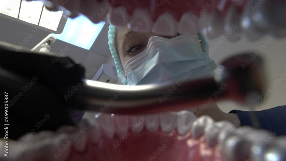 Dentist in protective mask inspects patient's teeth. View inside of mouth