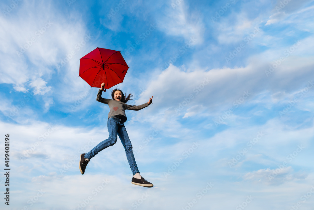 Little happy girl fly on background of blue cloudy sky holding red umbrella. Imagination, adventure, weather forecast, windy weather concept. Little happy girl fly on background of blue cloudy sky holding red umbrella. Imagination, adventure, weather forecast, windy weather concept.