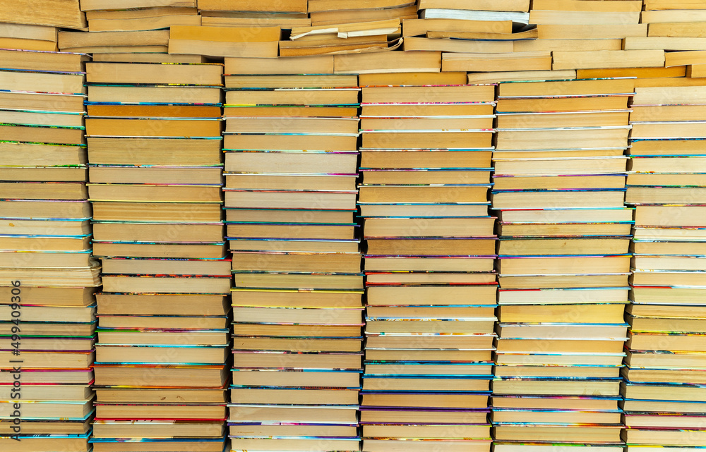 Endless wall of old books stack background. Colorful educational used books folded in many pile columns. Collecting in the library and how to choose only one book. horizontal Endless wall of old books stack background. Colorful educational used books folded in many pile columns. Collecting in the library and how to choose only one book. horizontal