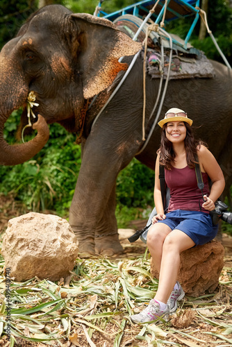 Another tick off my bucket list. Portrait of a young tourist sitting in a tropical rainforest with an elephant in the background.