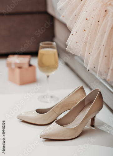 woman shoes and a glass of champagne and gift box next to a couch with festive dress. holiday or birthday party concept.