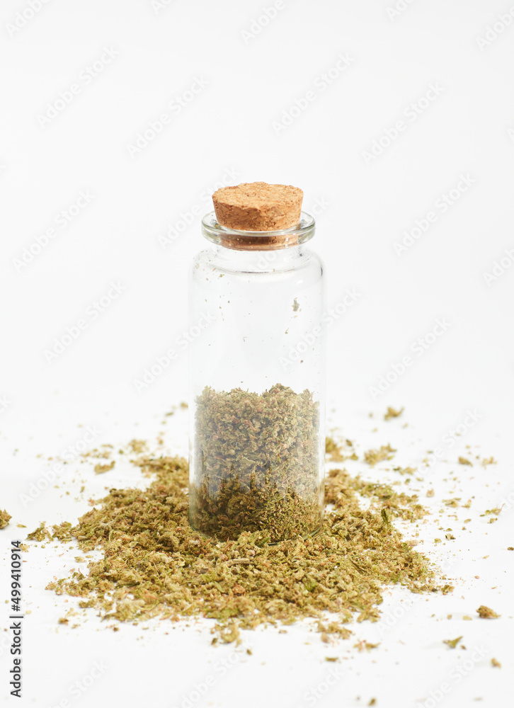 glass bottle with marijuana inside and cork stopper on crushed grass, white background glass bottle with marijuana inside and cork stopper on crushed grass, white background