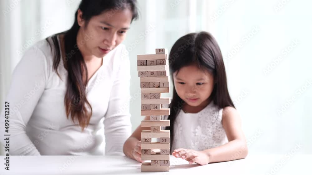 Happy family young Asian mother, child girl daughter and father spending time together, having fun, playing game Jenga wooden tower blocks at home. Concept of happy family, mothers, fathers, children Happy family young Asian mother, child girl daughter and father spending time together, having fun, playing game Jenga wooden tower blocks at home. Concept of happy family, mothers, fathers, children