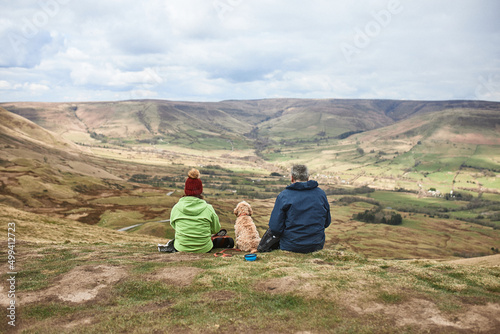 Mature couple outdoor sitting on the top of the mountain with their dog
