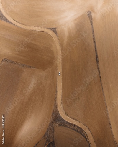 Minimal aerial top-down view of a car in a dry field in the middle of nowhere.