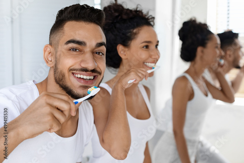 Dental Hygiene. Happy Young Arab Man And Woman Brushing Teeth In Bathroom