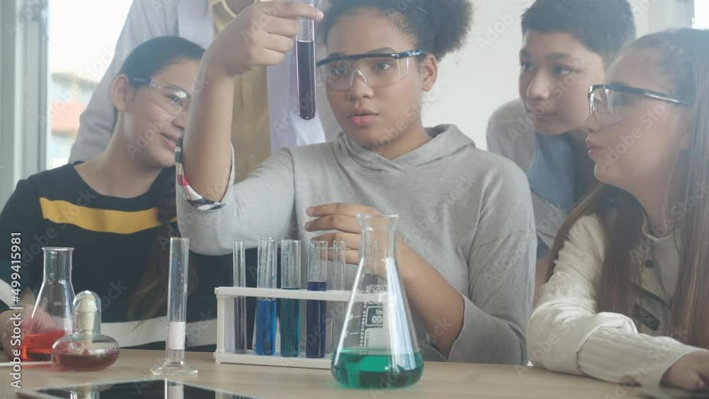 Young teacher teaching group student about science and explaining chemical for liquid in the lab of school, children studying and learning experiment science in the laboratory, education concept.