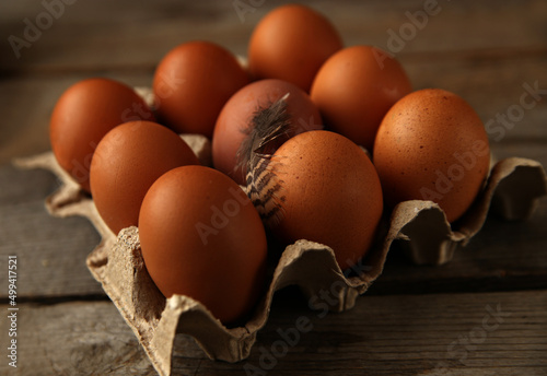 Brown chicken eggs in paper box on wooden surface