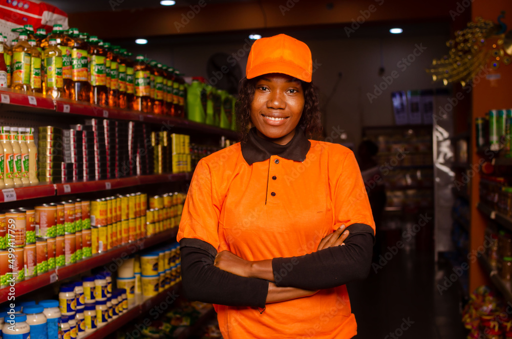 portrait of smiling shop woman standing and looking at the supermarket with crossing arms