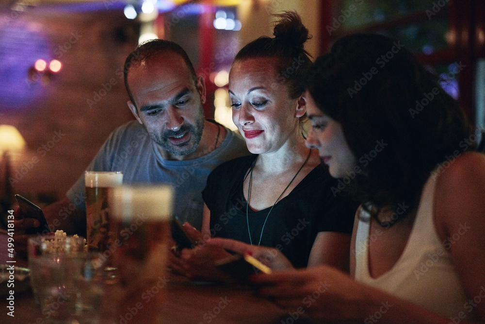Looks like I have a stalker in here. Shot of friends looking at something on a cellphone while sitting in the club.