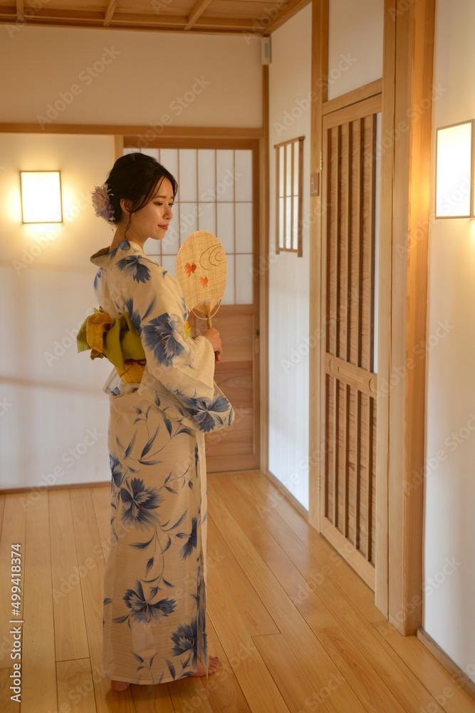 日本家屋の廊下でポーズをとる浴衣を着た若く美しい女性