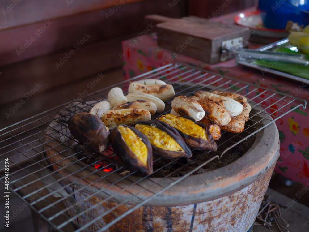 Bananas are grilled outdoors on a metal grid.