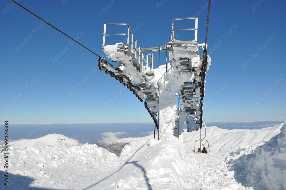 Ski lift chairs in the mountains. Back view of skiers in chairlift in snowy mountain. Bozdağ, Ödemiş, İzmir. Ski lift chairs in the mountains. Back view of skiers in chairlift in snowy mountain. Bozdağ, Ödemiş, İzmir.