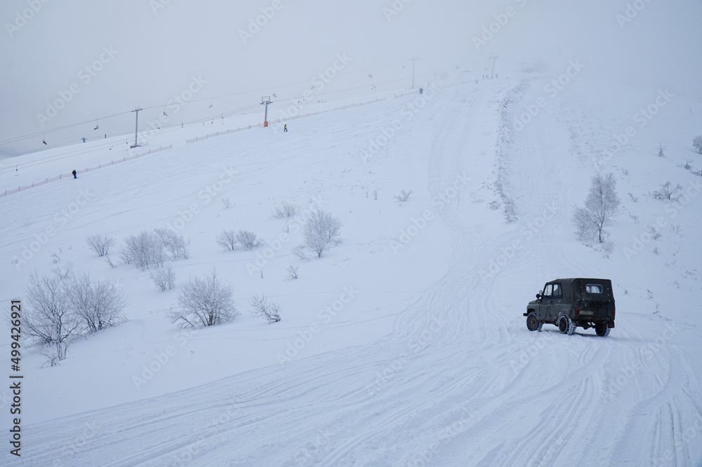 An old SUV drives through the winter Carpathian mountains. An old SUV drives through the winter Carpathian mountains.