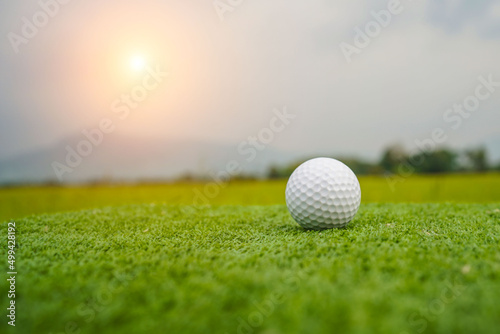 Golf ball on the green with warm tone and sunset. Golf ball on Green field golf course in morning time with soft sunlight.