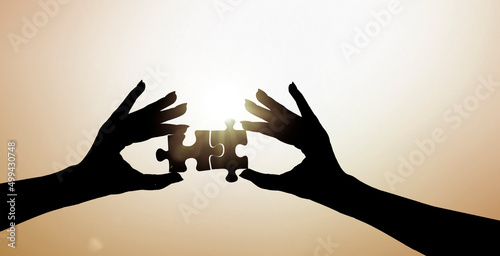 Zwei Hände fügen zwei Puzzleteile zusammen