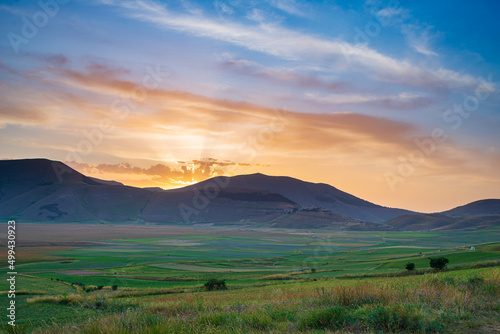 Beautiful sunset sky at Castelluccio di Norcia highlands, Italy. Blooming cultivated fields, famous colourful flowering plain in the Apennines. Agriculture of lentil crops.