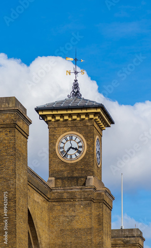 A clock in a yellow-brick tower. The watch shows 4:37 p.m.