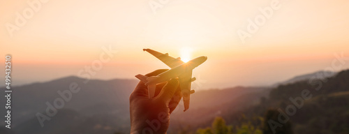Tela Hand holding a miniature airplane with the mountain view at sunrise, Summer vaca