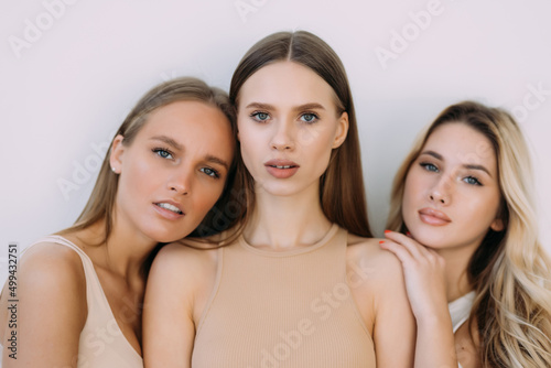 Three confident casual women standing on white studio background