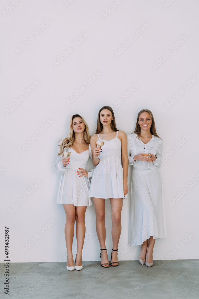 Three cute woman hold glasses toothy beaming smile wear mini dresses isolated on white background Three cute woman hold glasses toothy beaming smile wear mini dresses isolated on white background