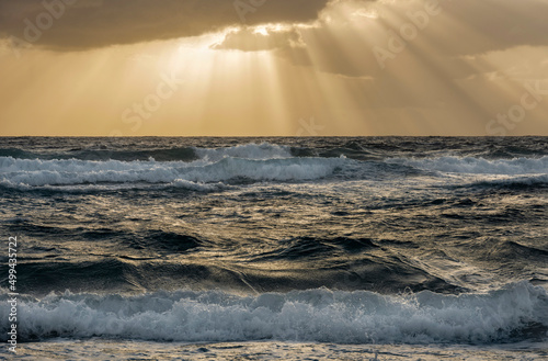 Sun rays streaking from clouds over ocean waves