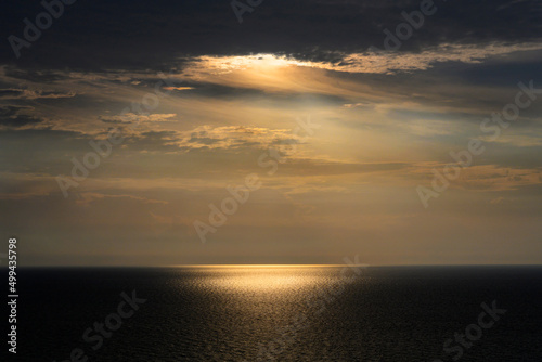 Sun shining through storm clouds and reflecting in ocean surface
