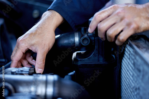 Hes hands on. Cropped shot of an unrecognizable male mechanic working on the engine of a car during a service.