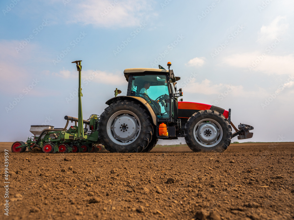Tractor drilling seeding crops at farm field. Agricultural activity.