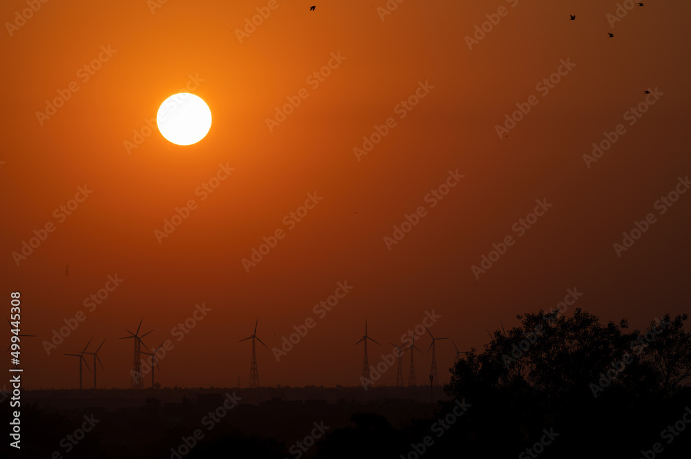 Sun rising on Thar desert, Jaisalmer, Rajasthan, India. Windmills in distant horizon.