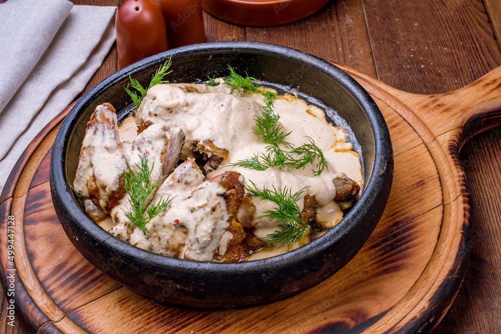 chicken chkmeruli in Georgian brown bowl side view chicken chkmeruli in Georgian brown bowl side view