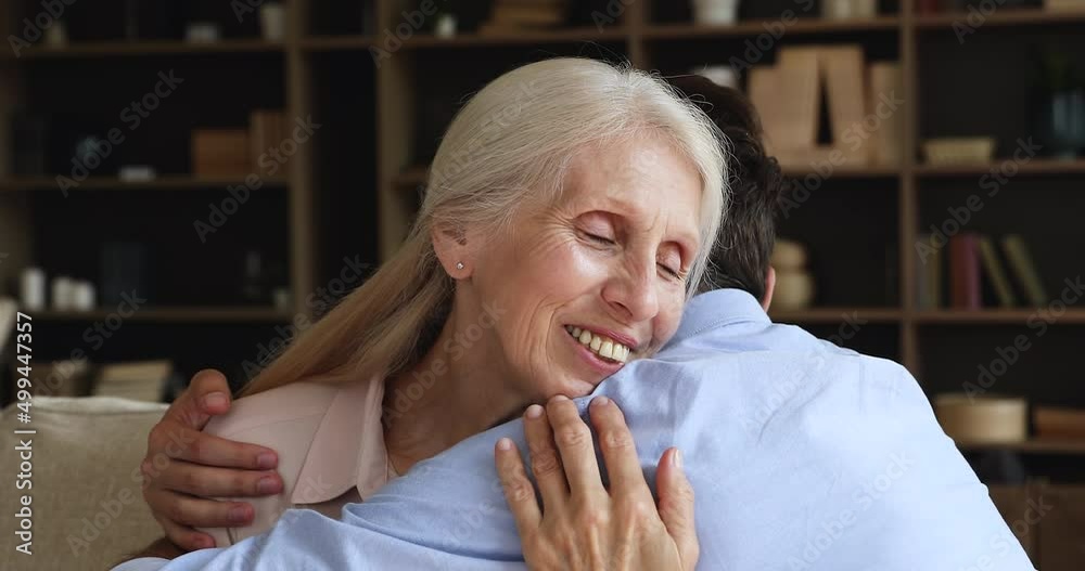 Happy mature grandmother pensioner meet adult grandchild with warm kind embraces hug beloved grownup grandson with affection feel support love. Older mom grown child son bonding after reconciliation