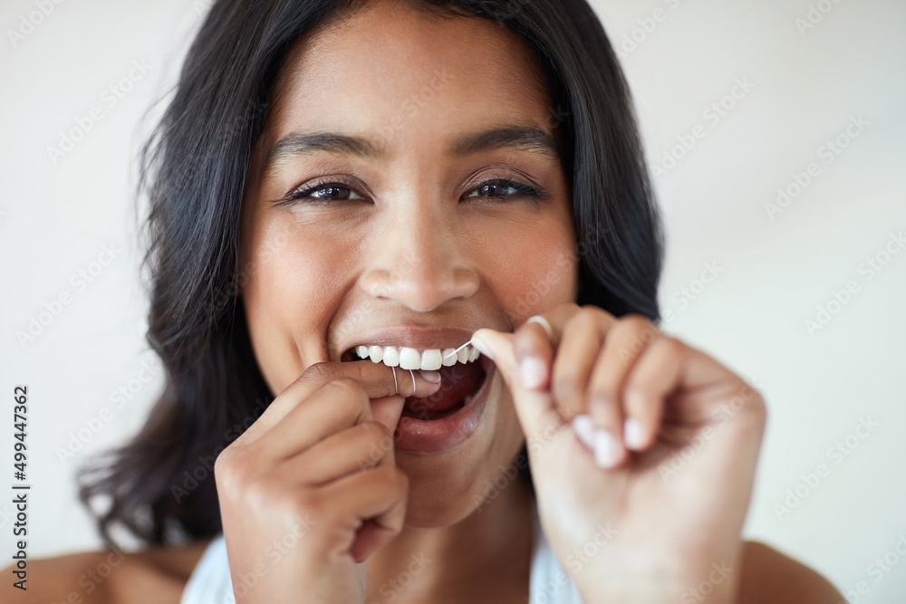 Making the health of my teeth a priority. Portrait of an attractive and happy young woman flossing her teeth. Making the health of my teeth a priority. Portrait of an attractive and happy young woman flossing her teeth.